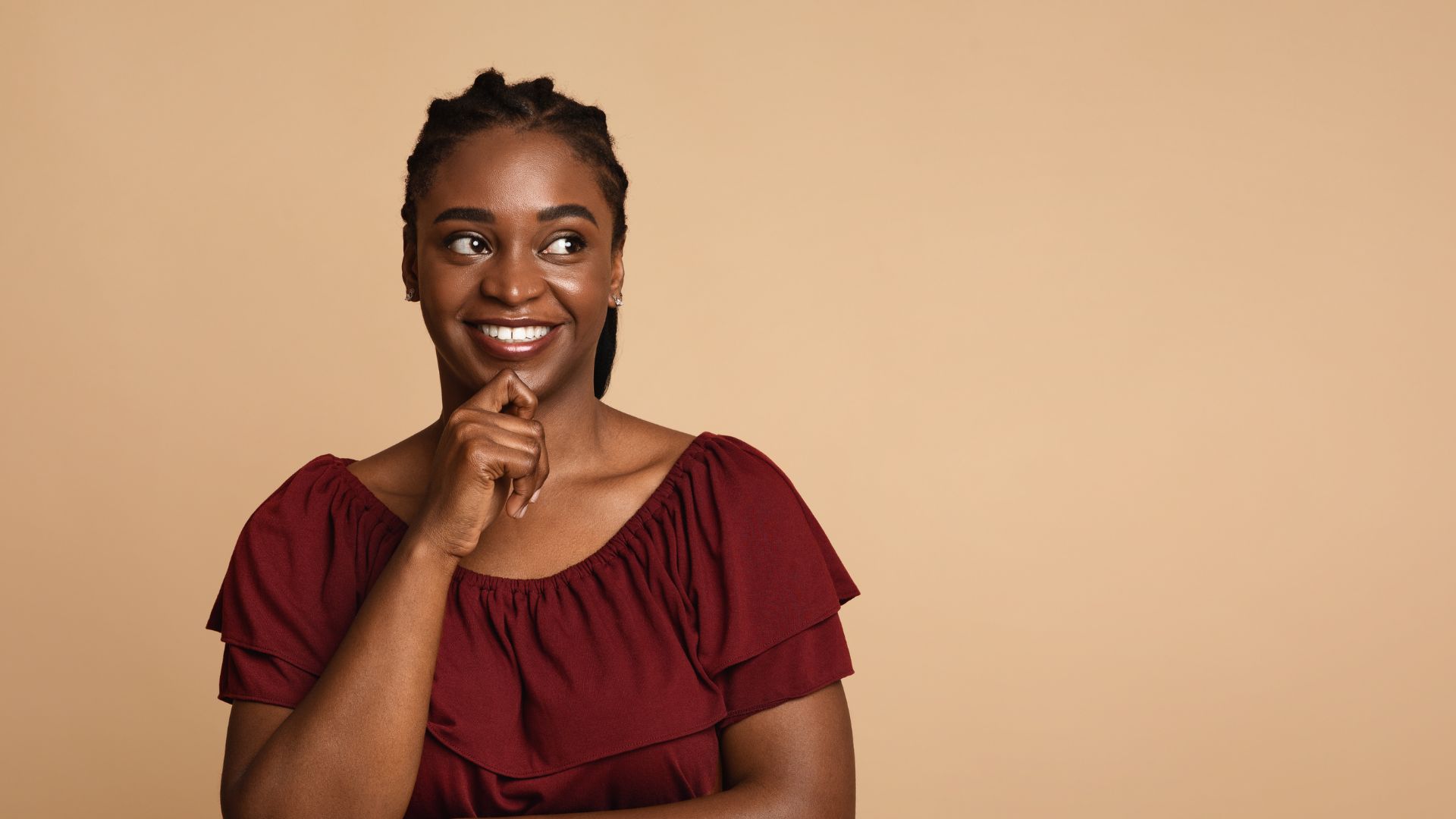 A woman with her knuckle to her chin having happy thoughts